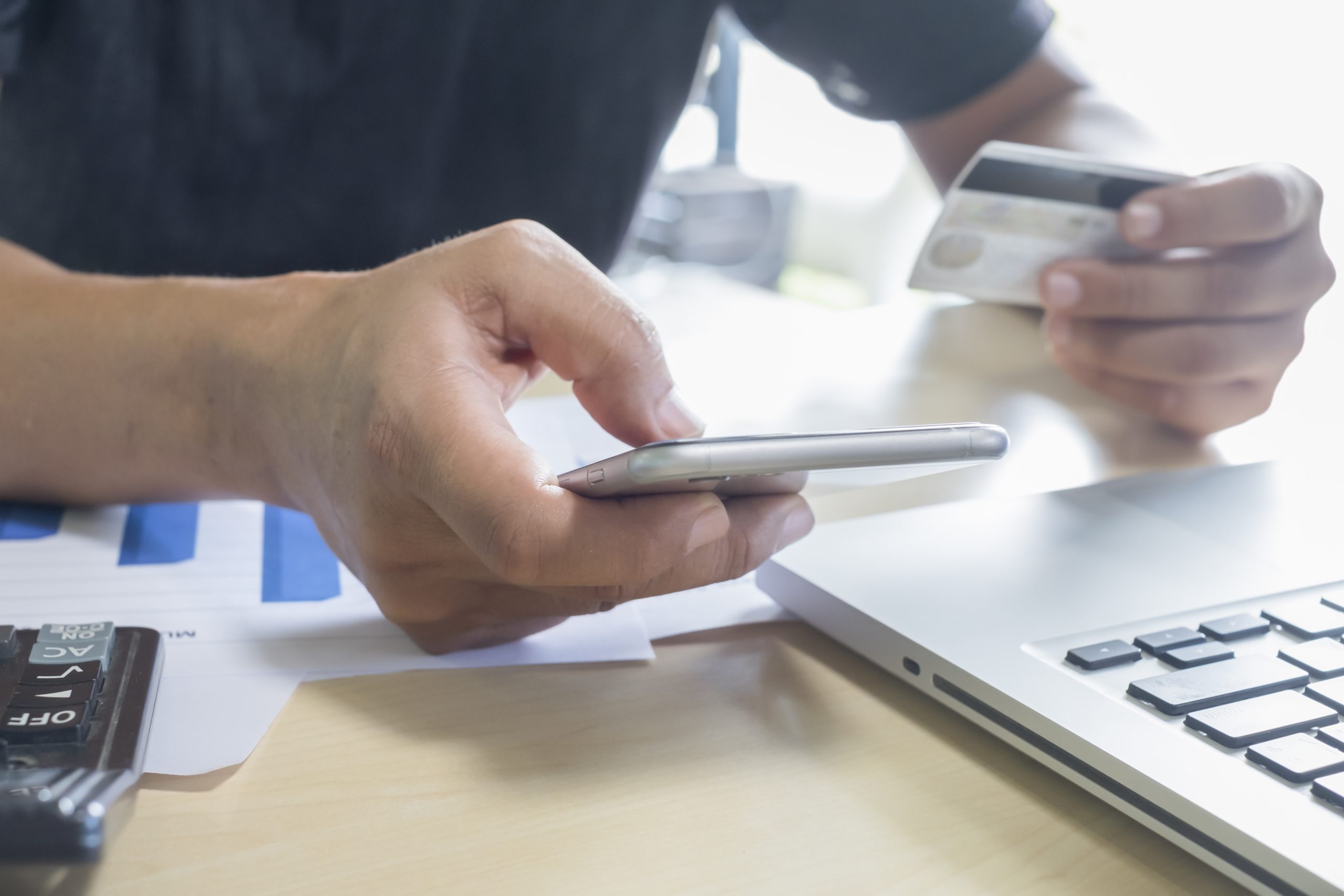 homem segurando telefone celular e cartão de crédito para contratar Pré-pago e pós-pago